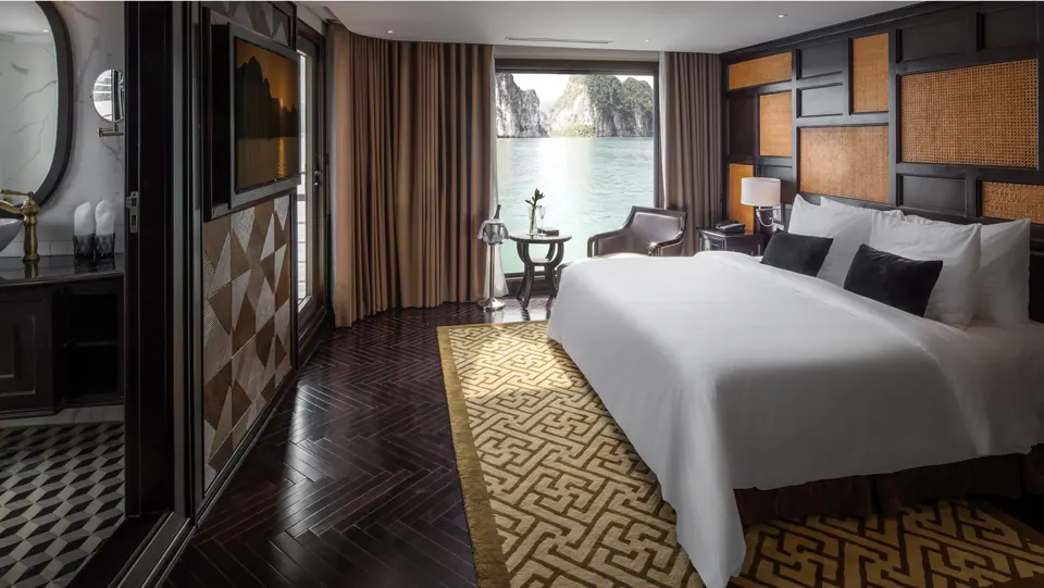 Captain Suite with a large bed, dark wood panels and terrace doors onto the bay