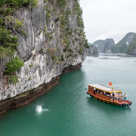 A small boat waiting under a sea cliff for climbers