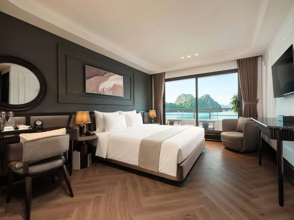 Ocean Balcony cabin with a double bed, armchair and a wide window looking out to limestone islands