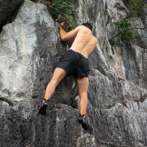 A climber working up a short limestone boulder