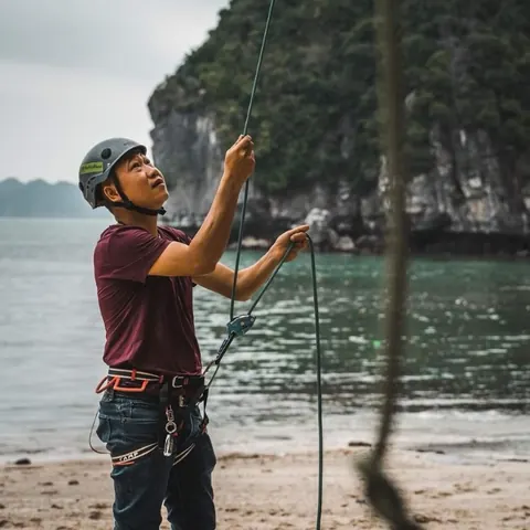 A climbing guide holding the rope at the foot of a sea cliff