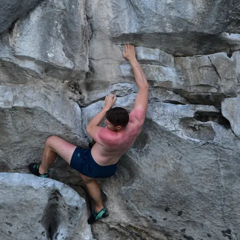 A climber reaching for a hold on grey limestone