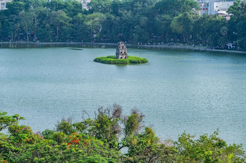 Turtle Tower on a small green island in Hoan Kiem lake, Hanoi, seen from above over calm water and tree-lined shores