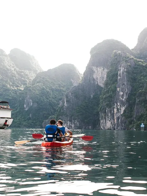 Two people paddling a kayak between steep cliffs
