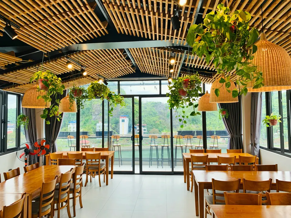 Wooden cafe at Rustic House with rattan lamps, hanging plants and a view of the karst hills