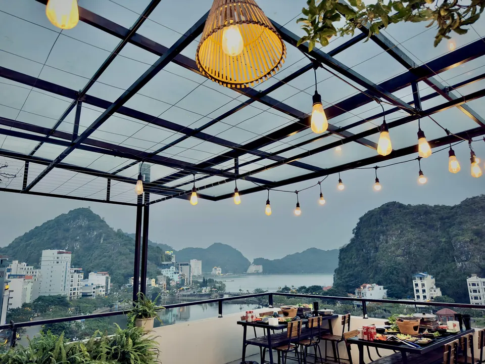 Rooftop terrace at Rustic House under string lights, looking over Cat Ba bay