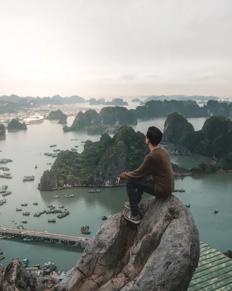 A traveller sitting on a rock above Lan Ha Bay looking out over the islands