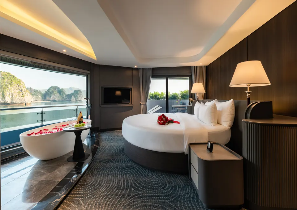 Suite with a round bed, a freestanding bathtub by a large window and a view of the bay