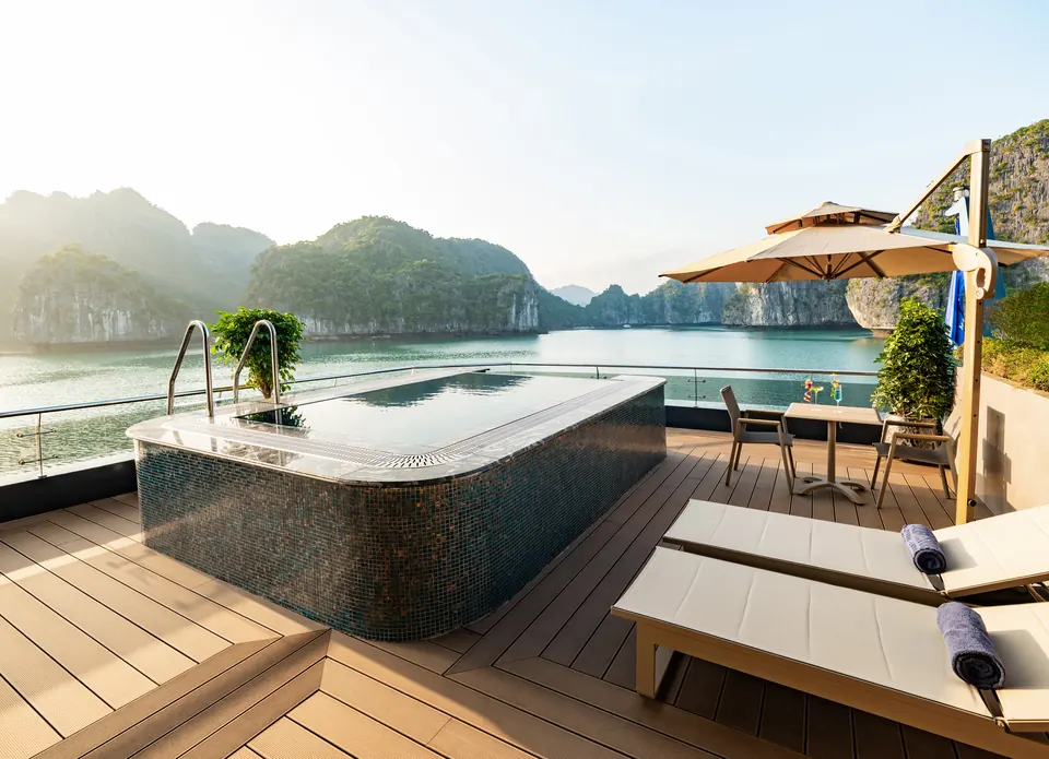 Private suite terrace with a jacuzzi tub, sun loungers and a parasol facing the islands